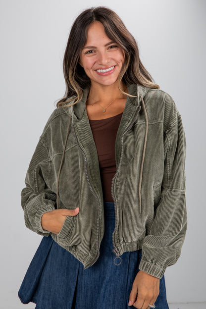 Woman wearing a green corduroy jacket against a plain background
