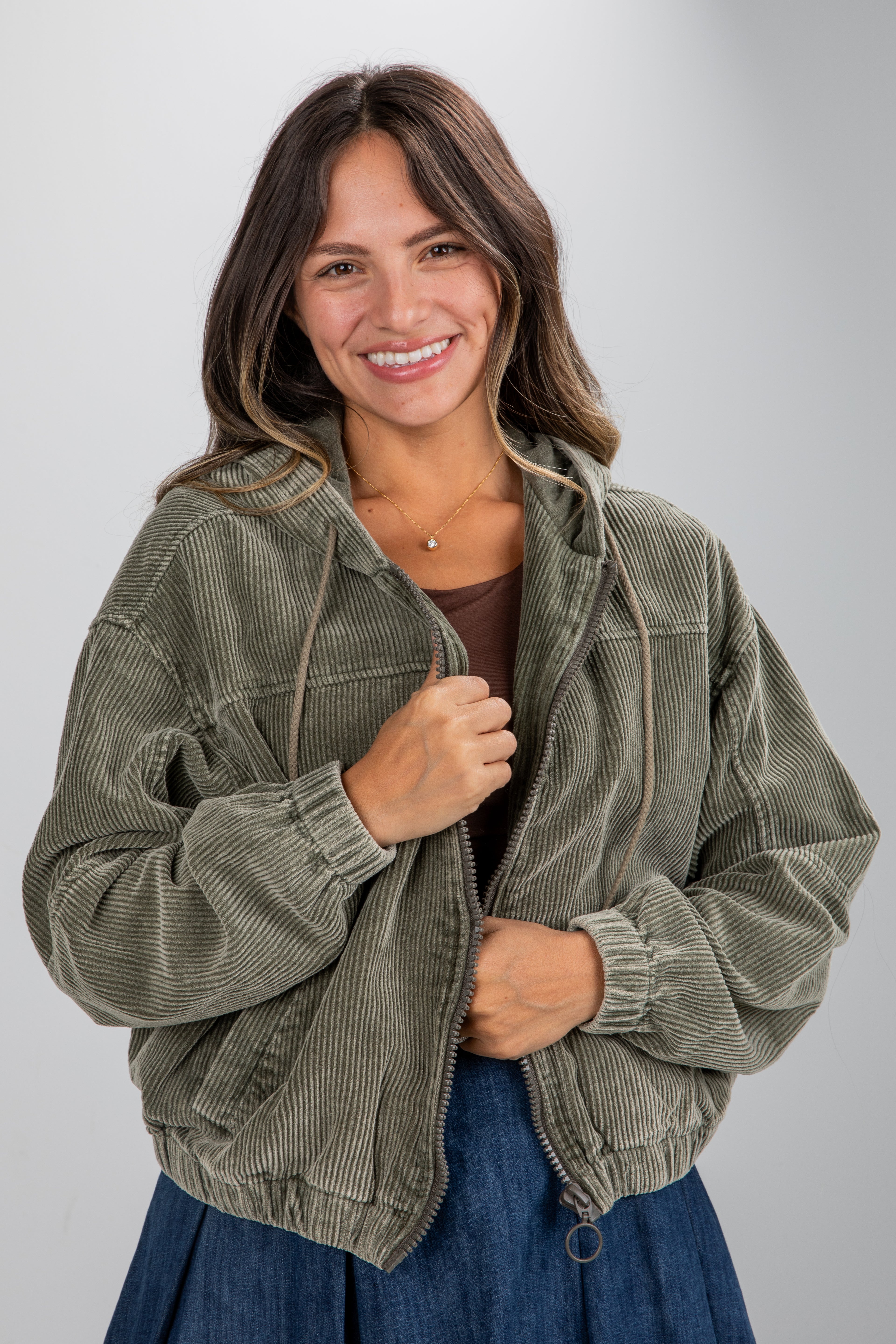 Woman wearing a green corduroy jacket on a gray background