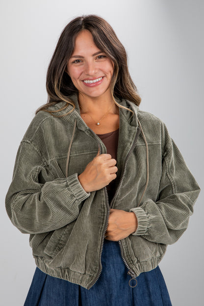 Woman wearing a green corduroy jacket on a gray background