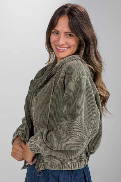 Woman wearing a green corduroy jacket against a plain background
