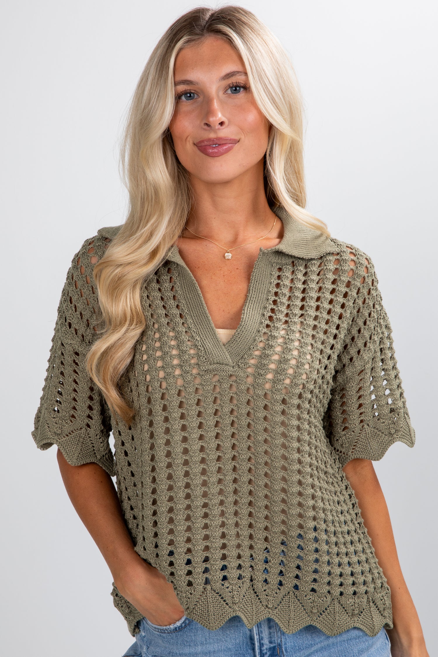 Woman wearing a green crochet top against a plain background