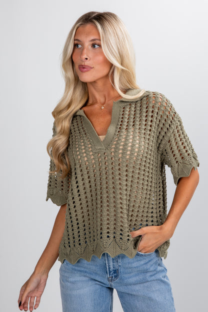 Woman wearing a green crochet top and blue jeans on a plain background