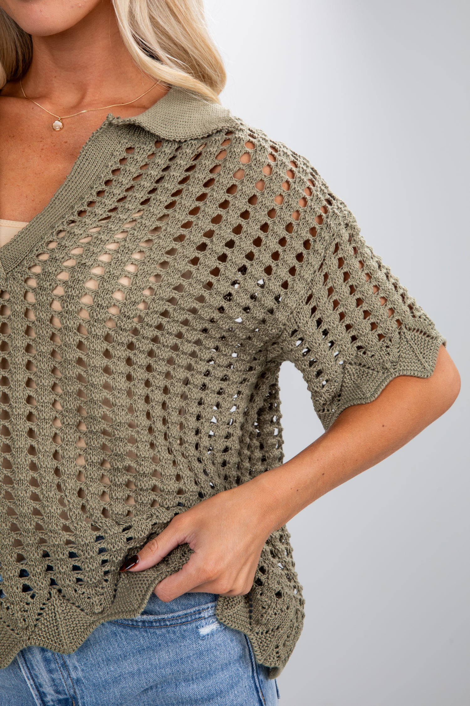 Woman wearing a green crochet top with a plain background