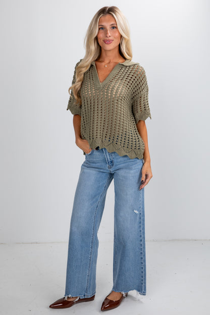 Woman wearing a green crochet top and blue jeans on a white background