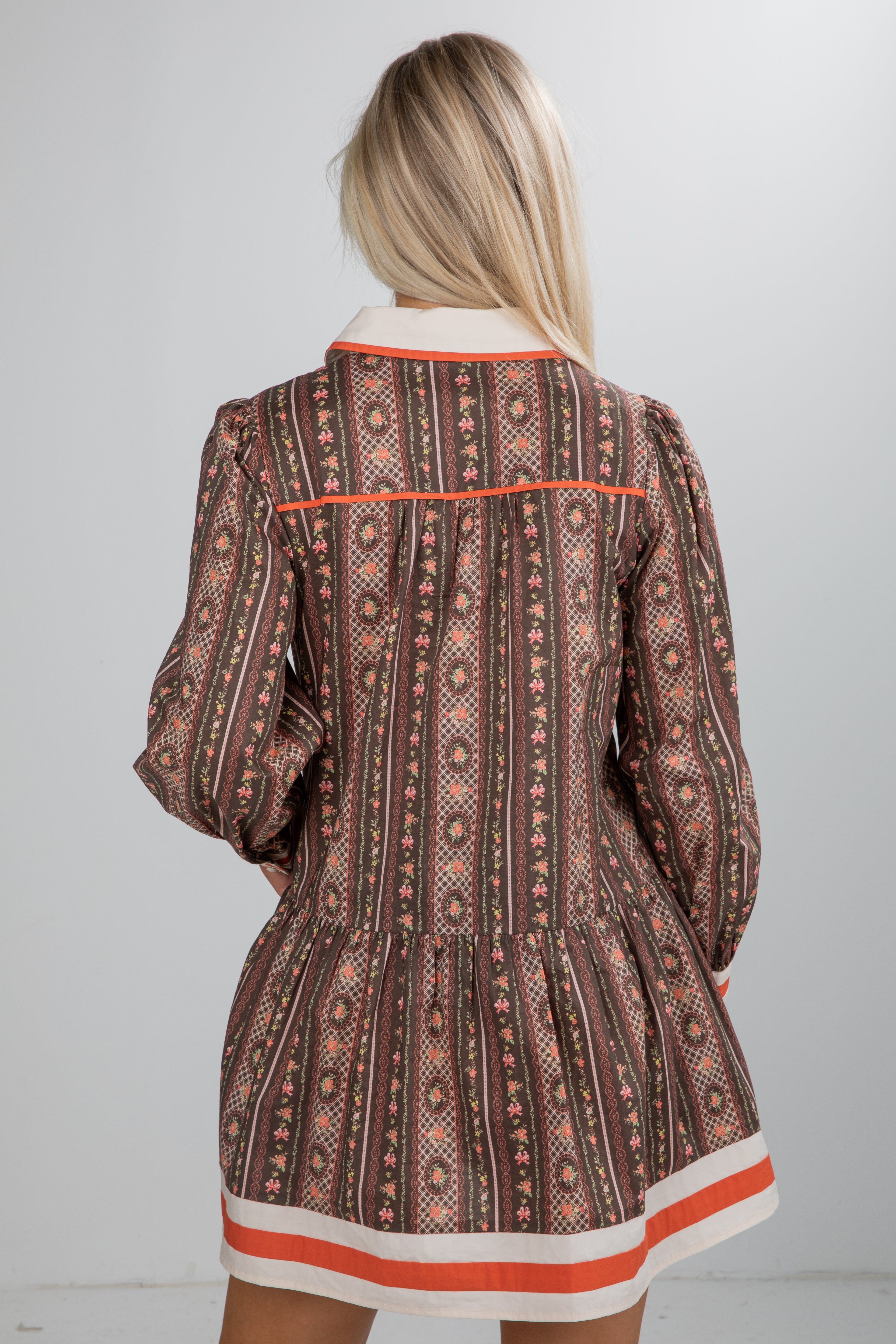 Patterned dress with long sleeves and a white collar on a plain background