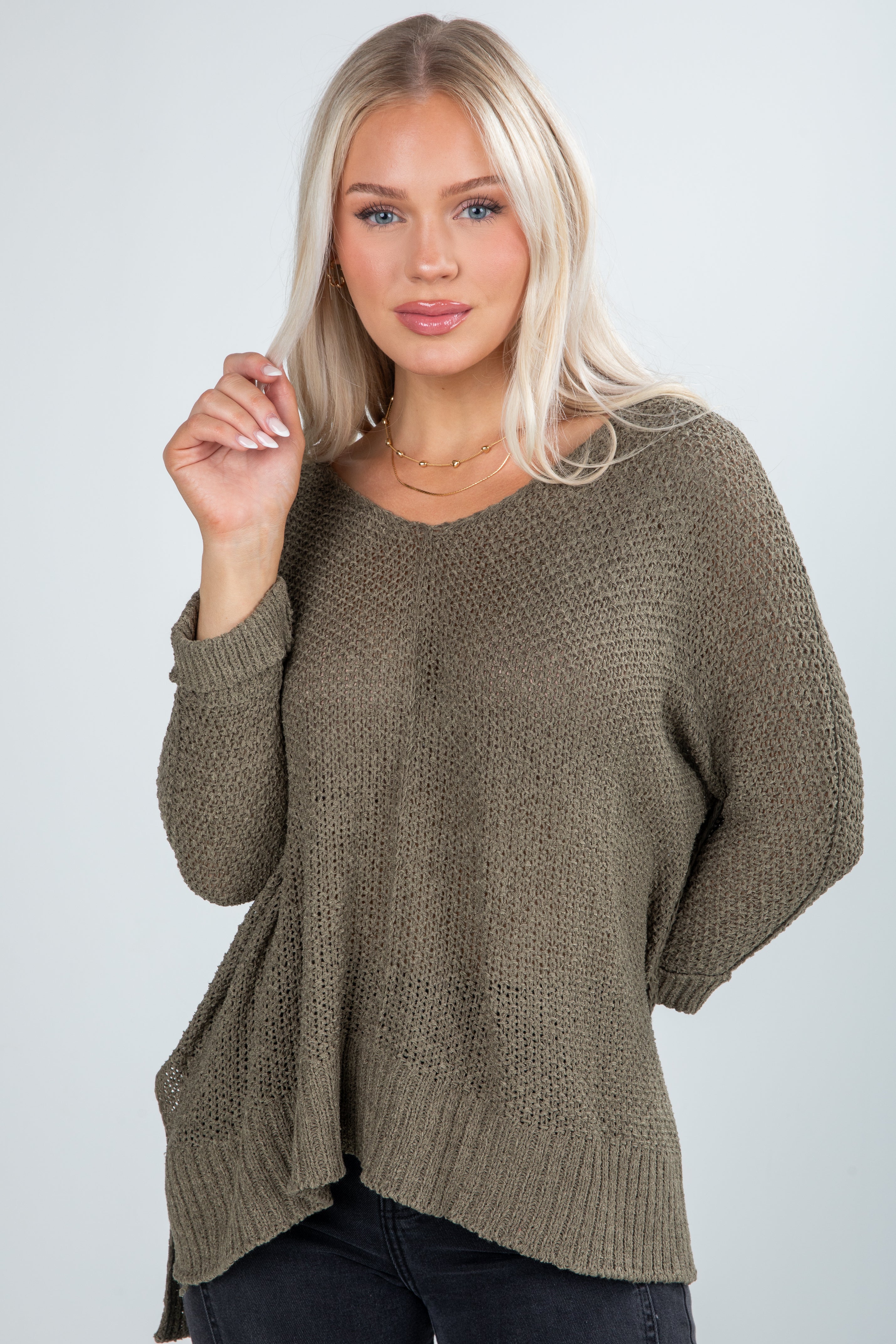 Woman wearing a brown knitted sweater against a plain background
