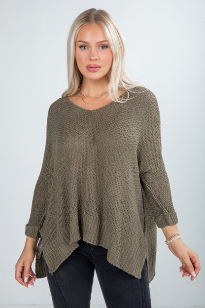 Woman wearing a brown knit sweater against a plain background
