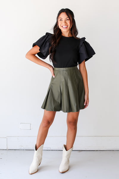 model wearing an olive Leather Mini Skirt with white boots