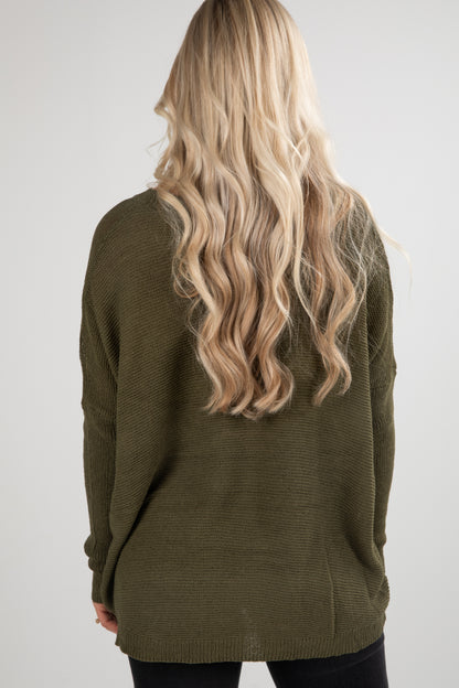 Person wearing a green sweater with long blonde hair on a white background