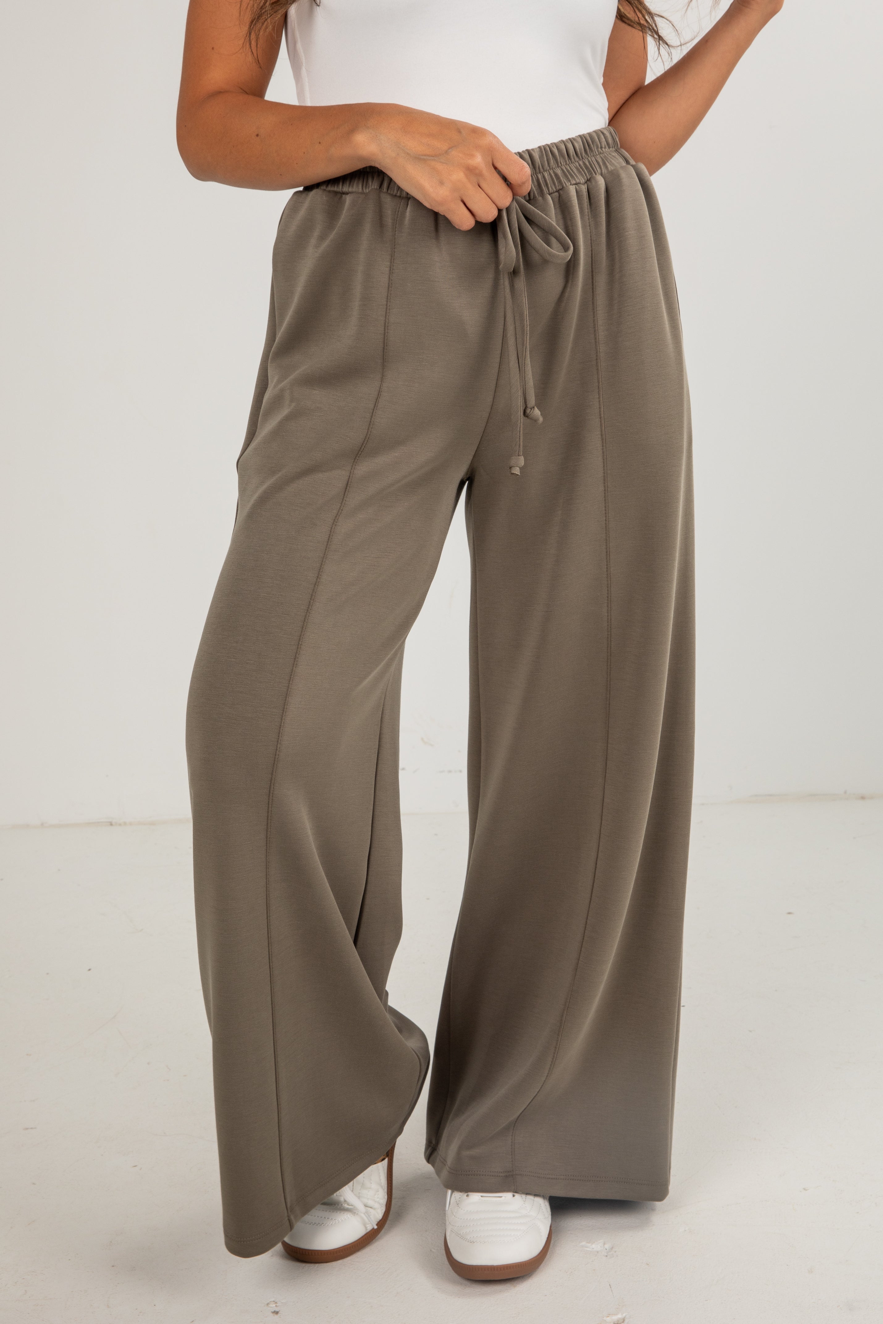 Person wearing brown wide-leg pants on a white background