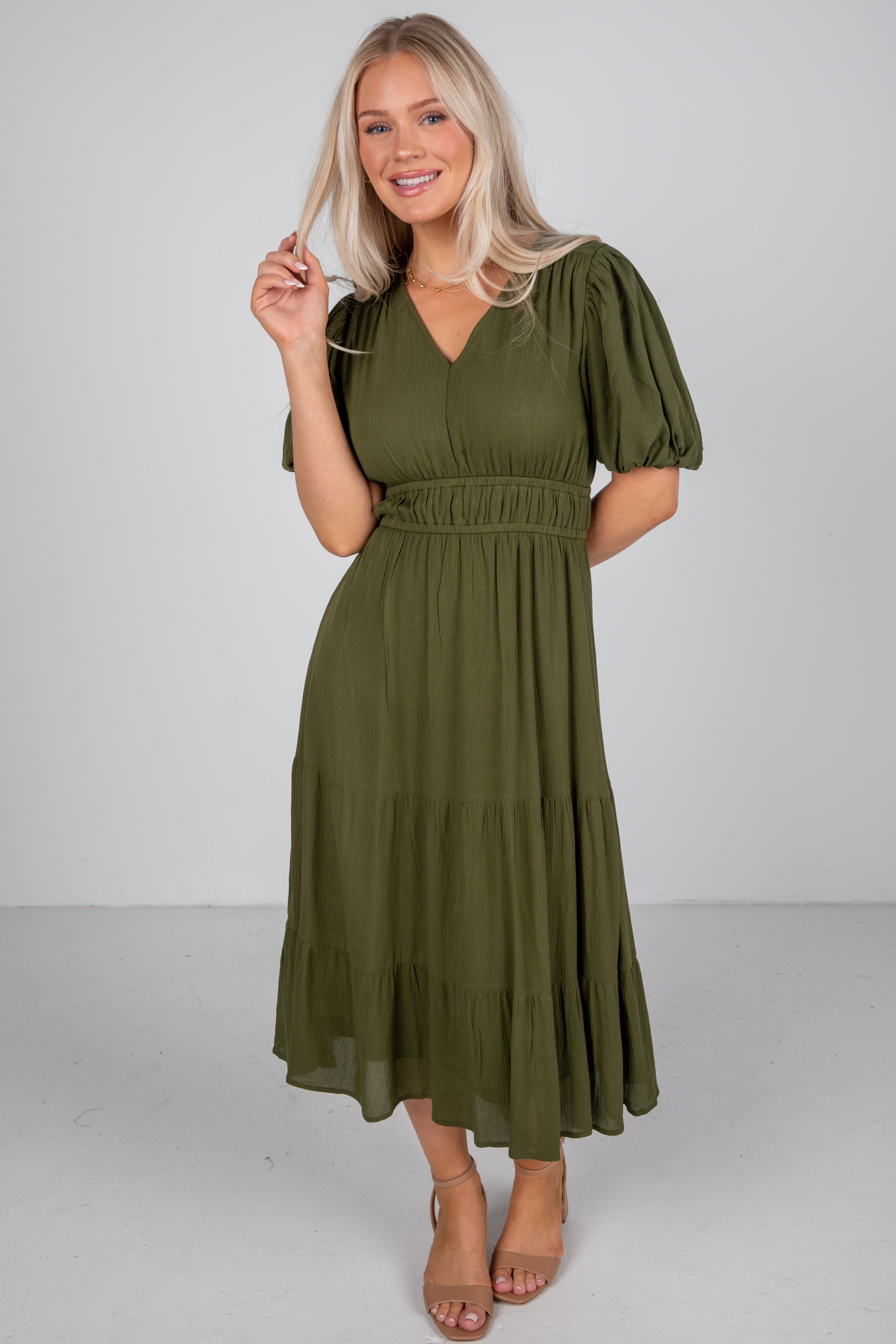 Woman wearing an olive green dress against a white background