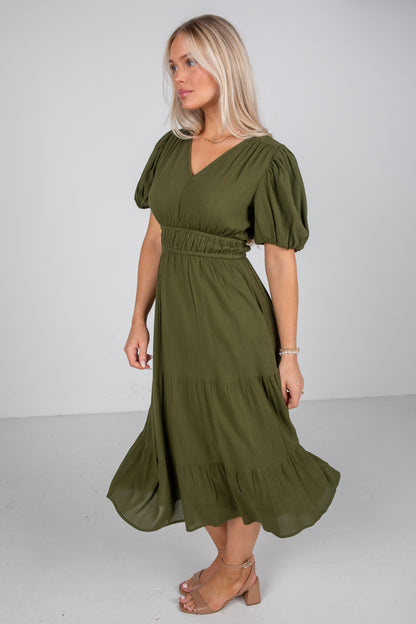 Woman wearing an olive green dress with puffed sleeves on a white background
