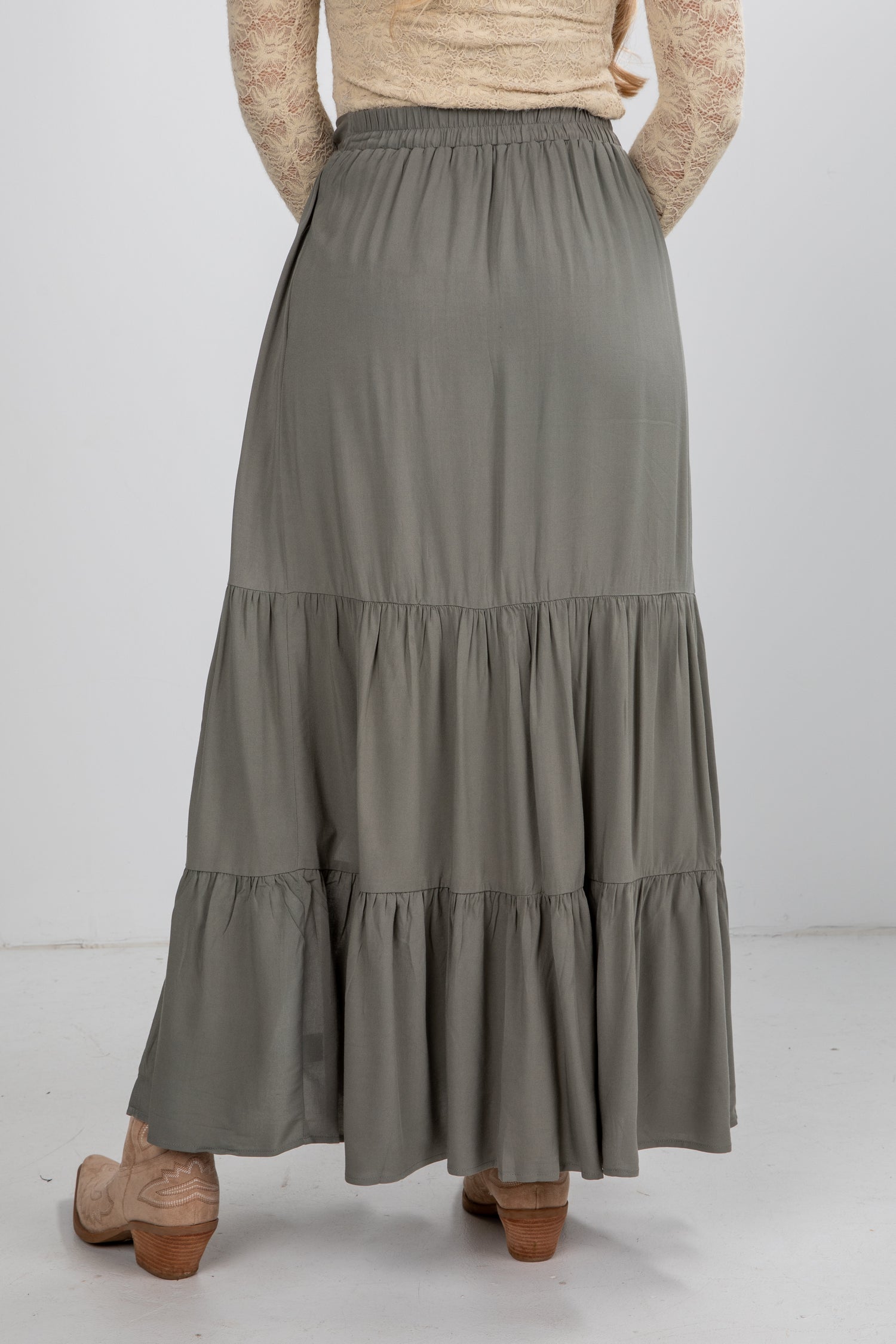 Person wearing a long, tiered gray skirt on a white background