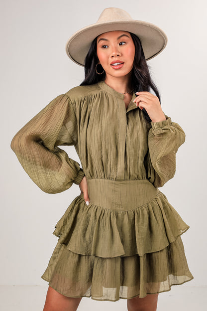 Woman wearing a green dress with long sleeves and a hat on a white background