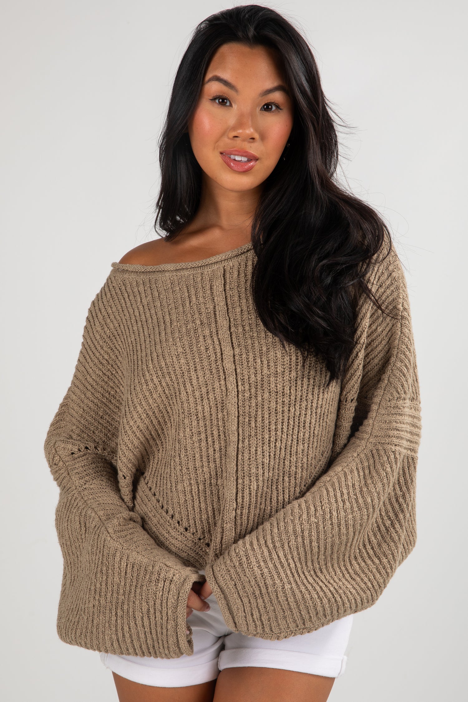 Woman wearing a beige sweater against a white background