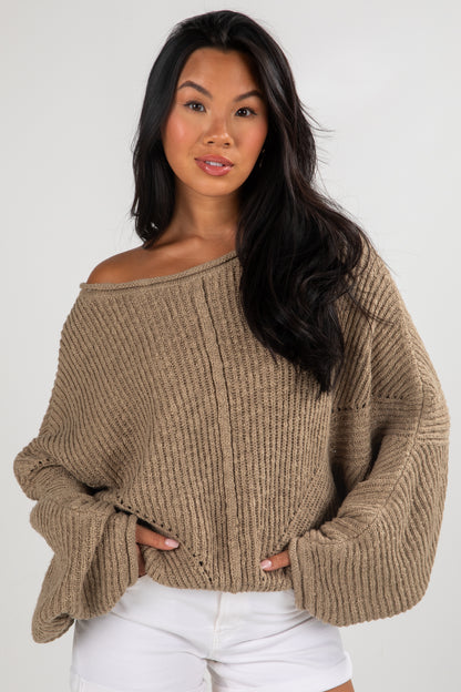 Woman wearing a beige sweater against a white background