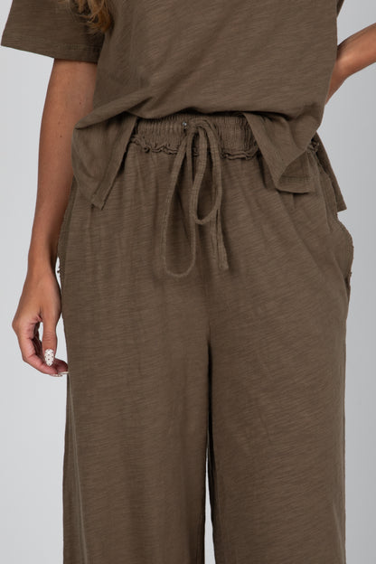Brown outfit with a top and wide-leg pants on a plain background