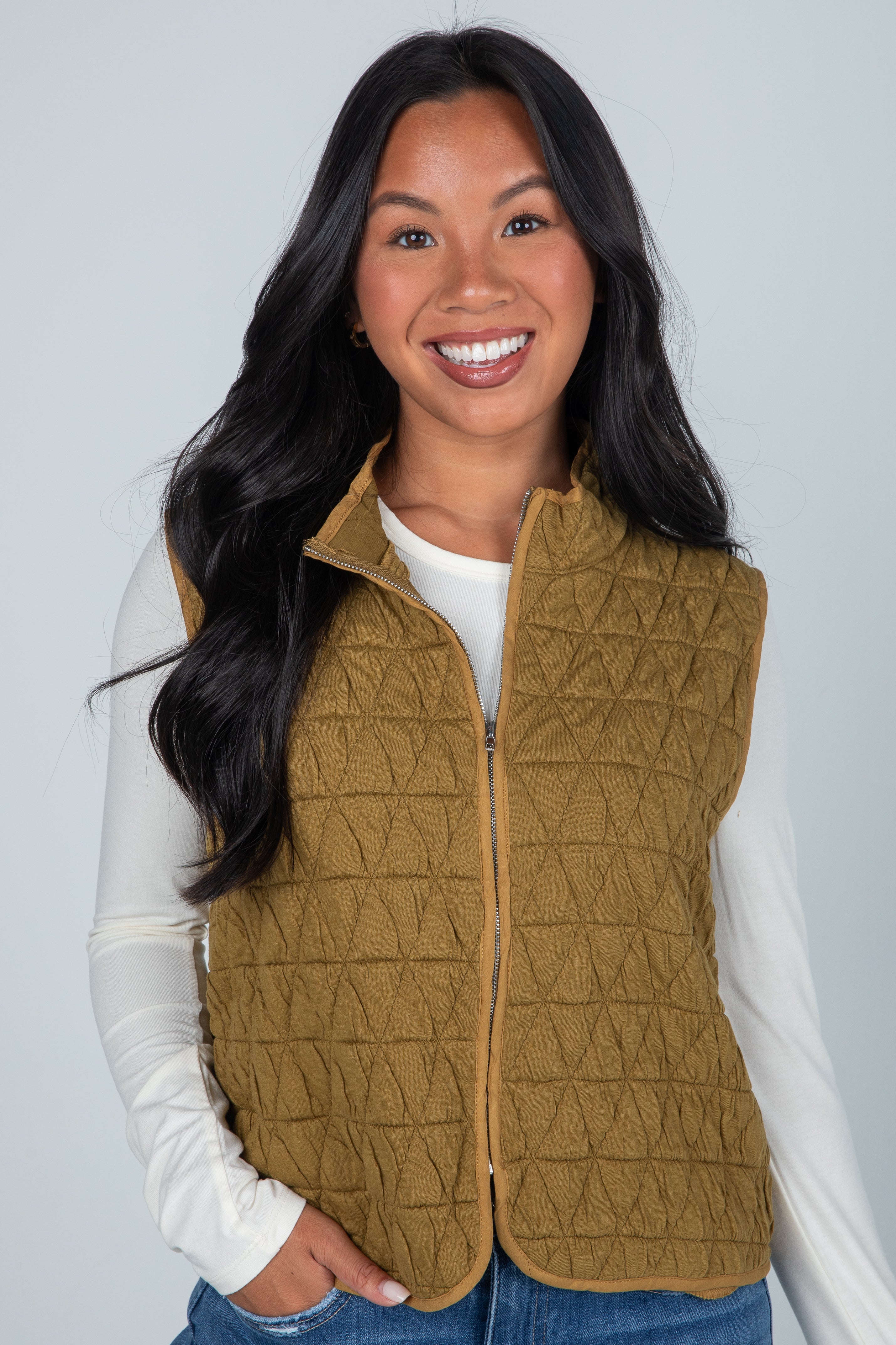 Woman wearing a brown quilted vest against a plain background