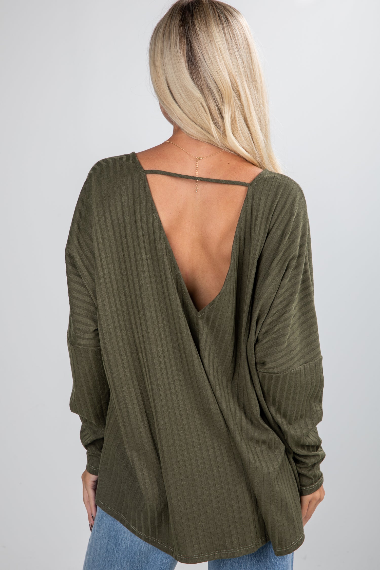 Green long-sleeve top with open back worn by a person on a plain background