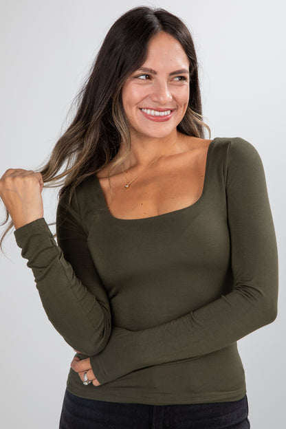 Woman wearing an olive green long-sleeve top against a white background