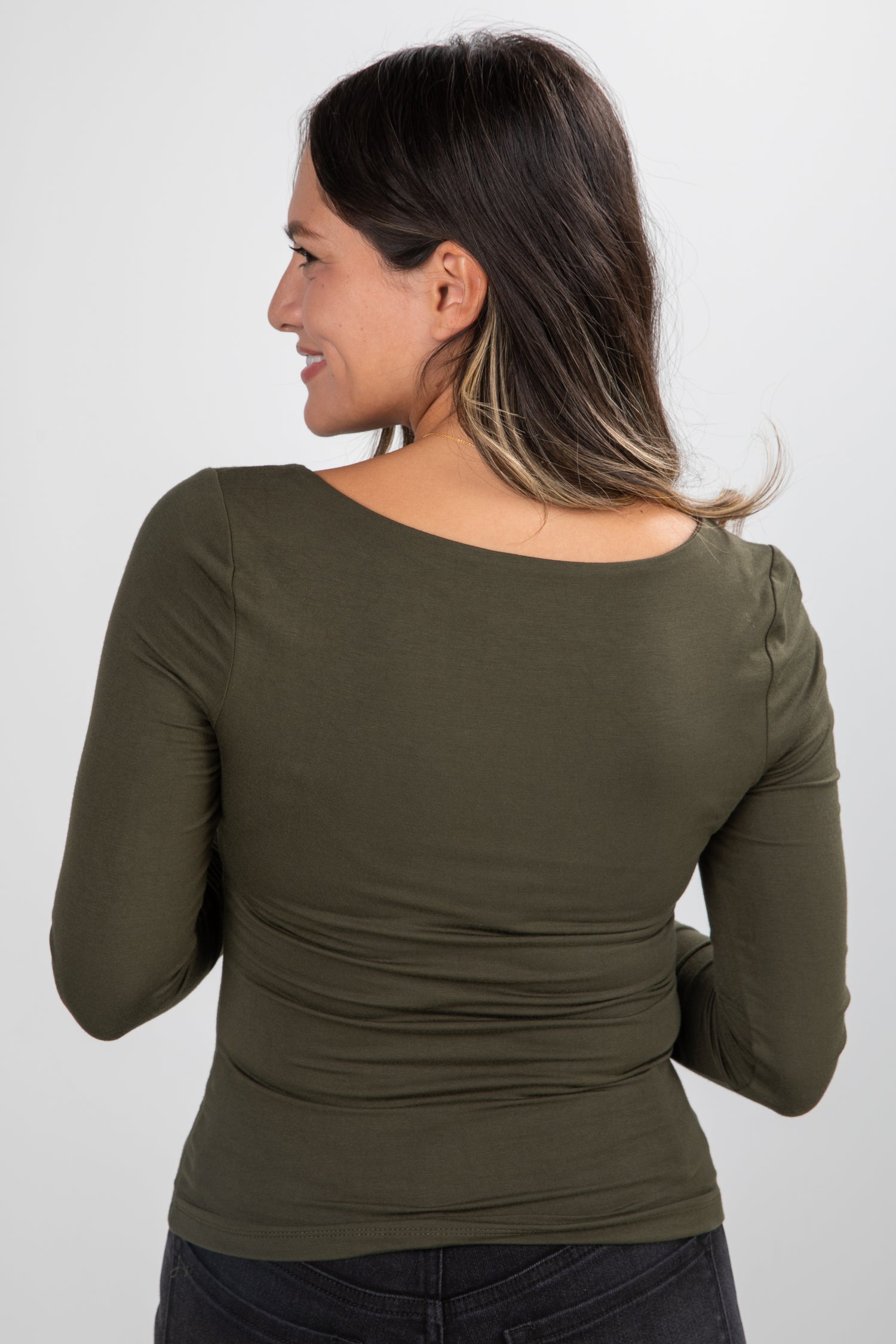 Woman wearing an olive green long-sleeve top against a white background