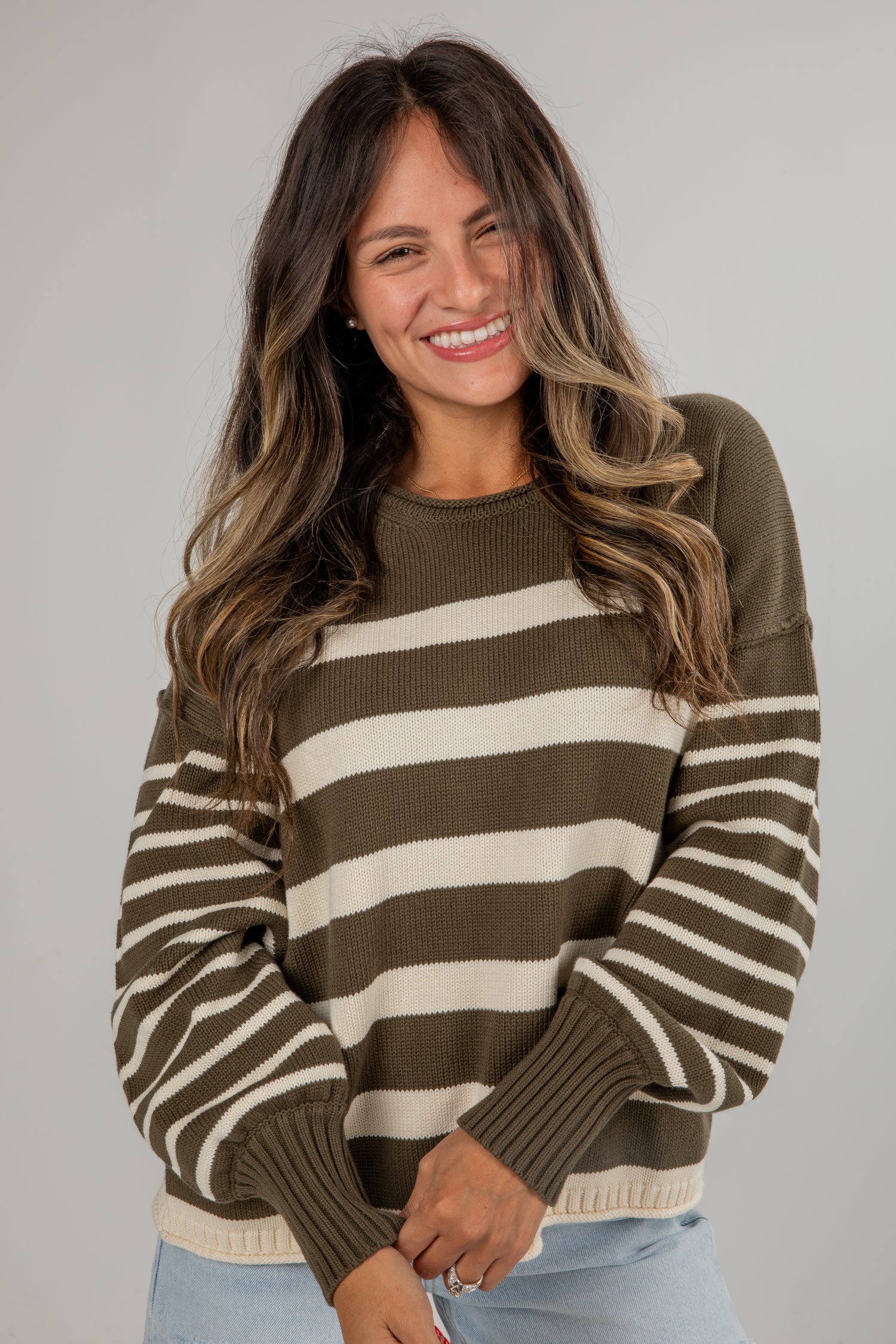 Woman wearing a brown and beige striped sweater against a plain background
