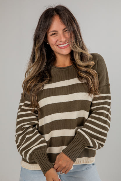 Woman wearing a brown and beige striped sweater against a plain background