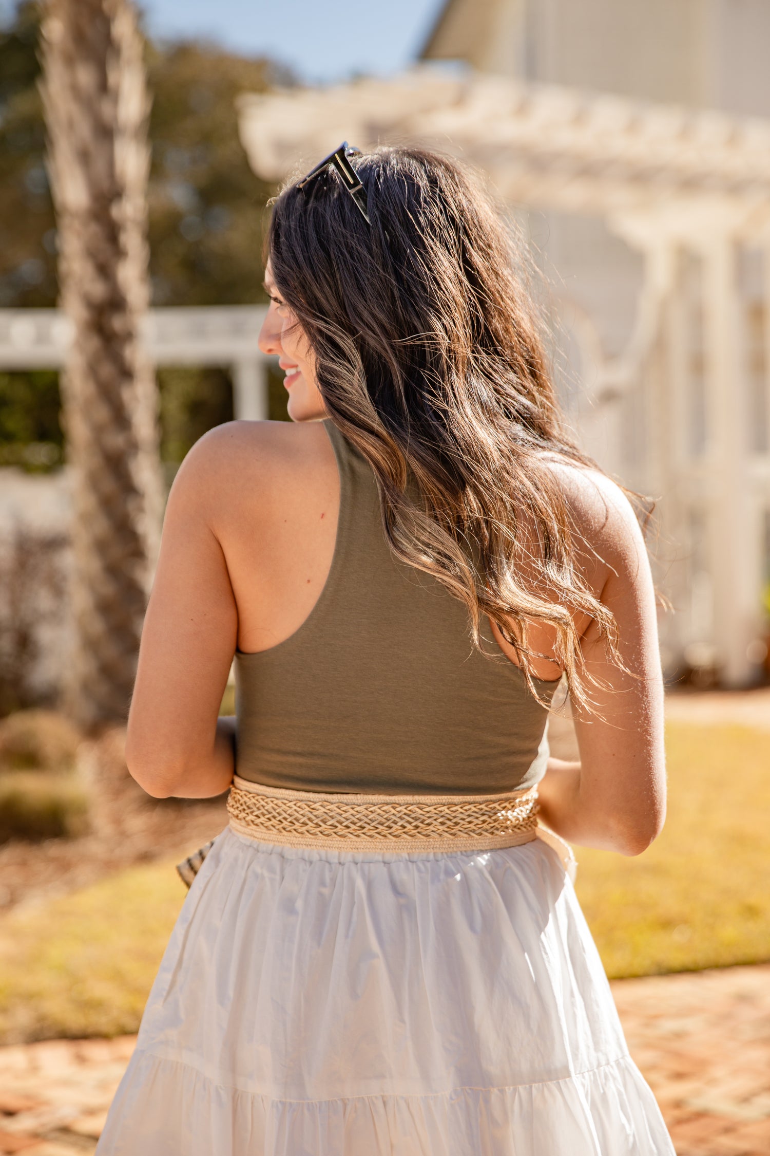 Woman wearing a green top and white skirt with a blurred background