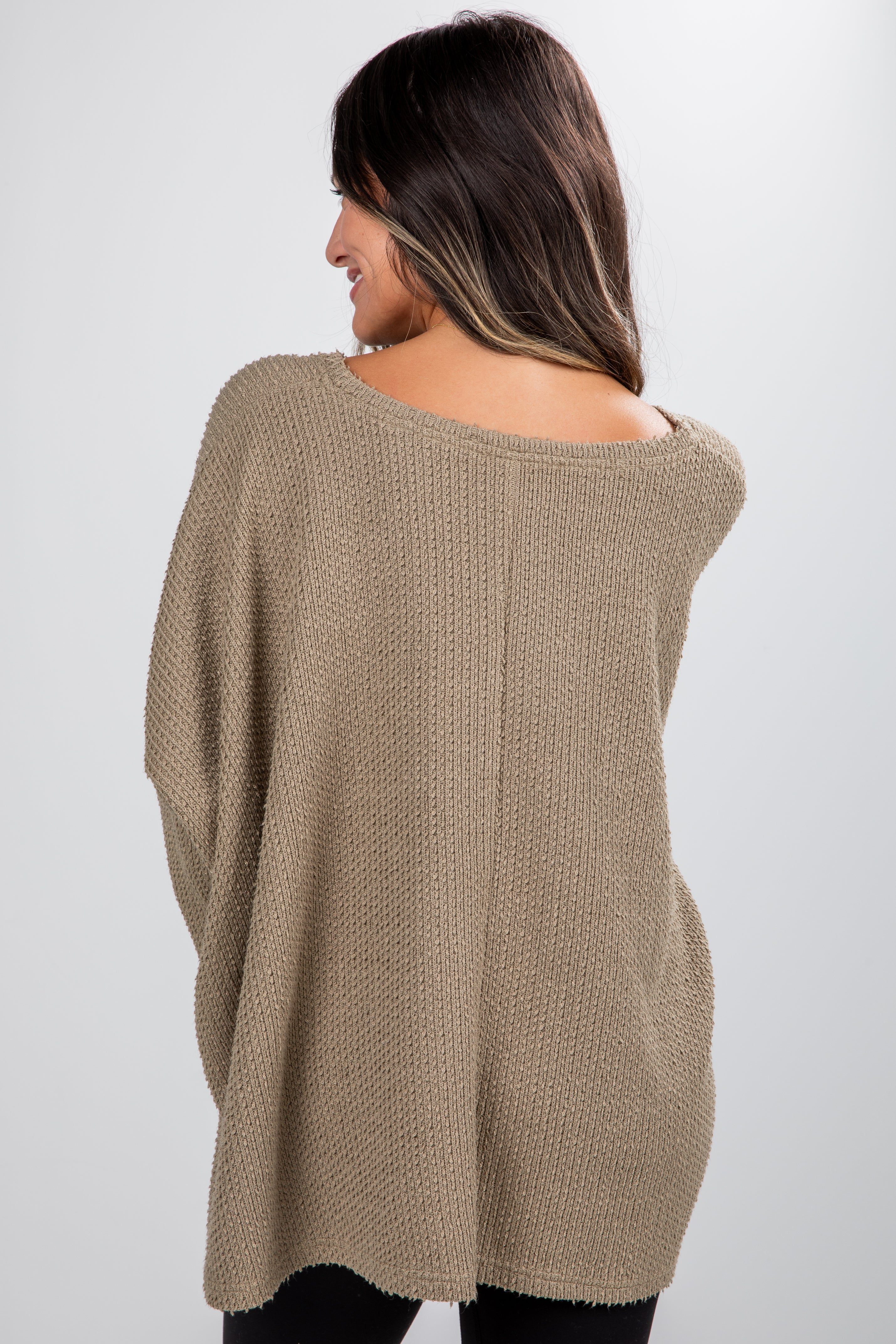 Woman wearing a beige sweater against a white background