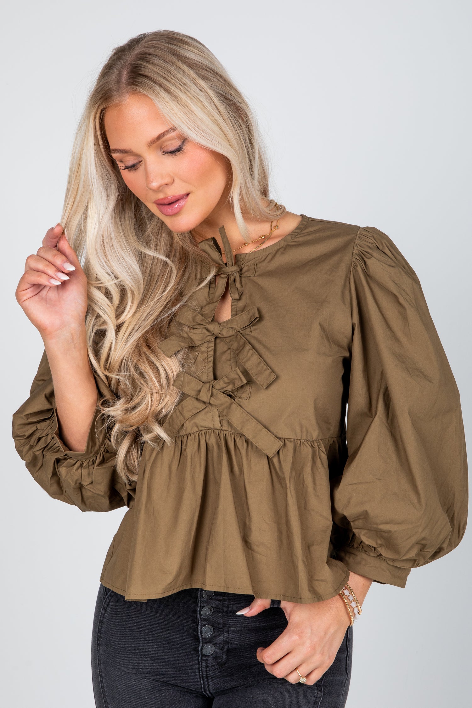 Woman wearing a brown blouse with ruffled details on a white background