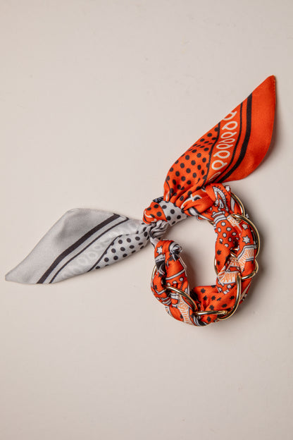 Two patterned hair scarves tied into knots on a beige background