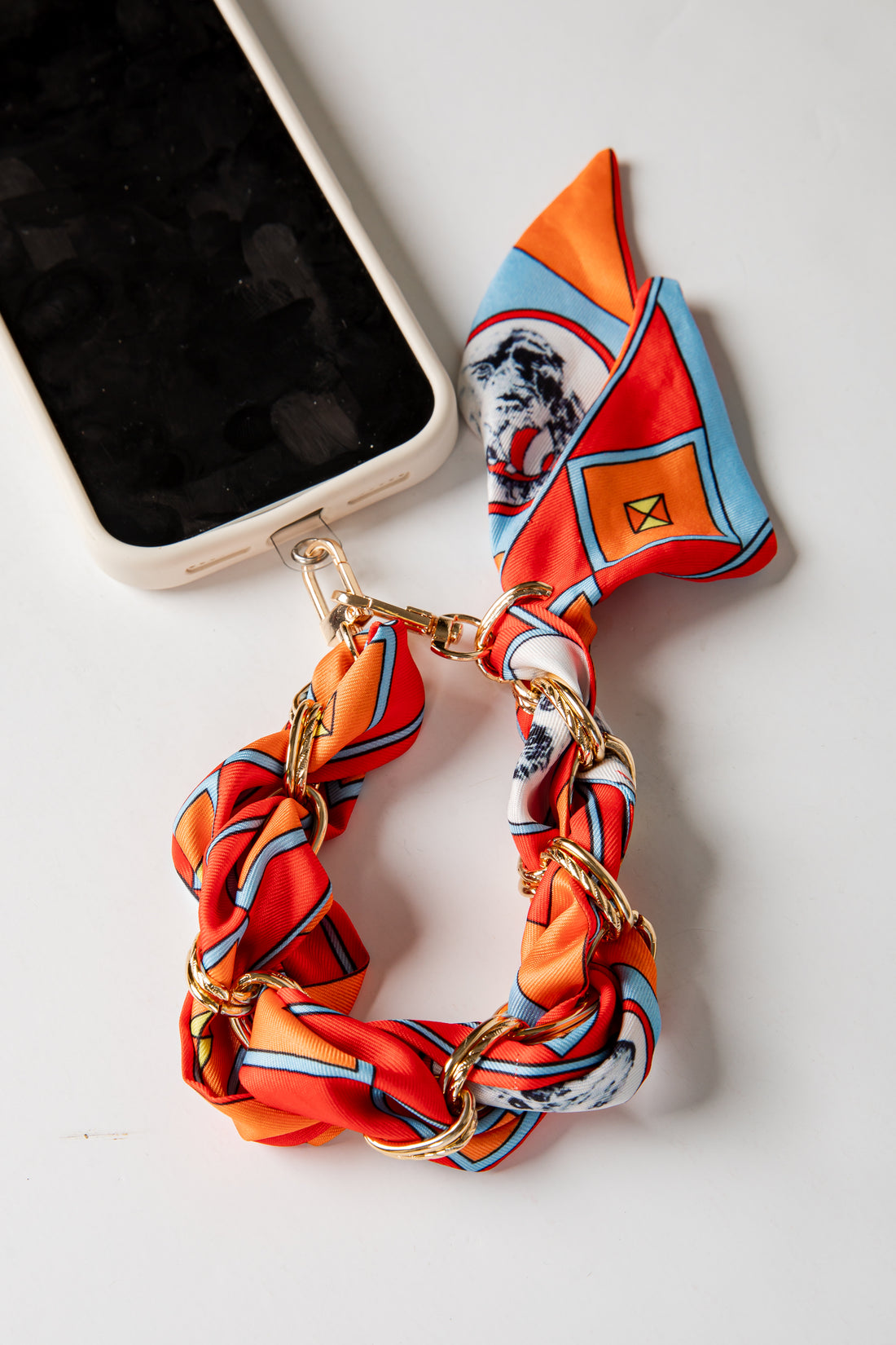 Colorful scarf with gold chain and phone case on a white background