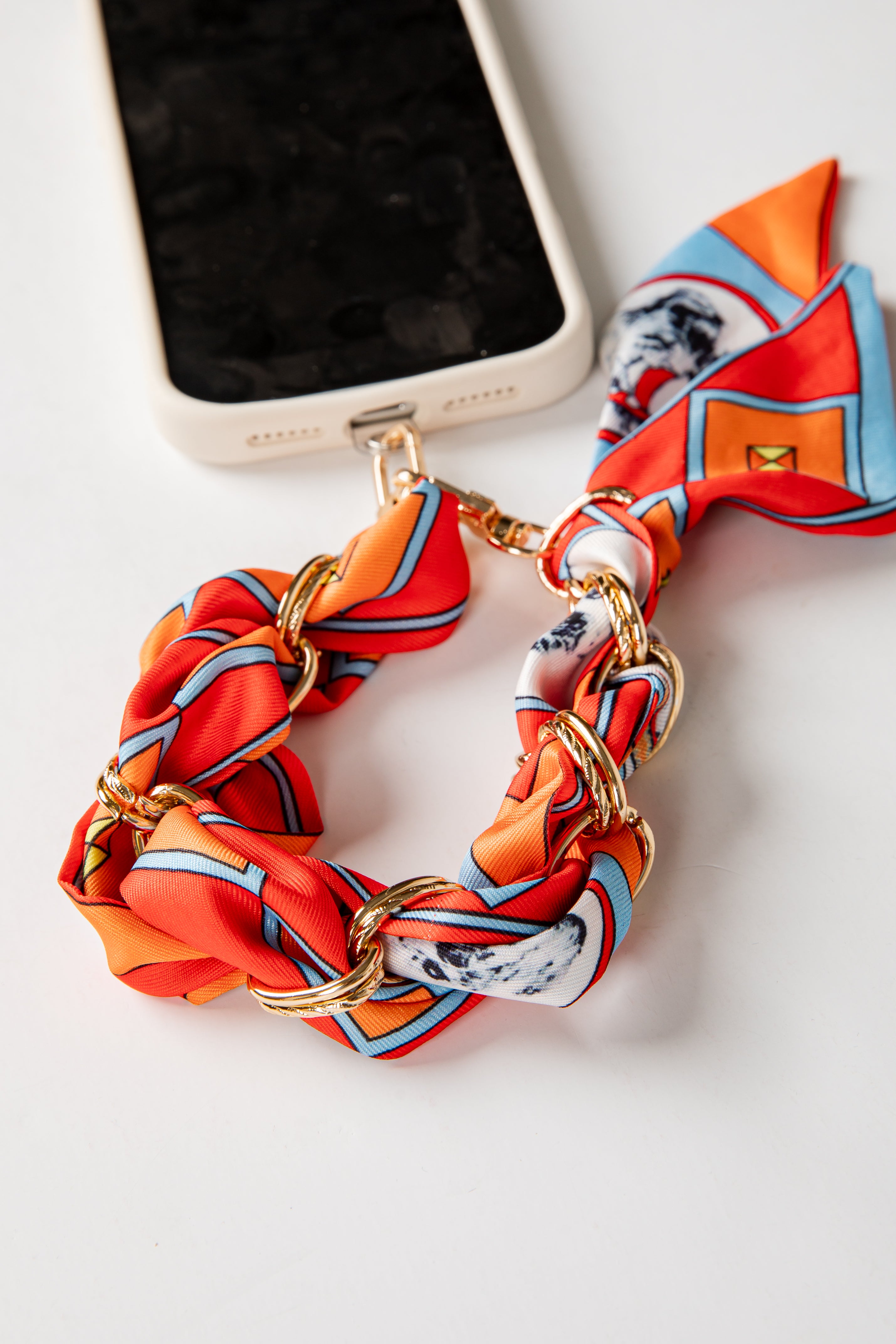 Colorful phone accessory with gold chain on a white surface