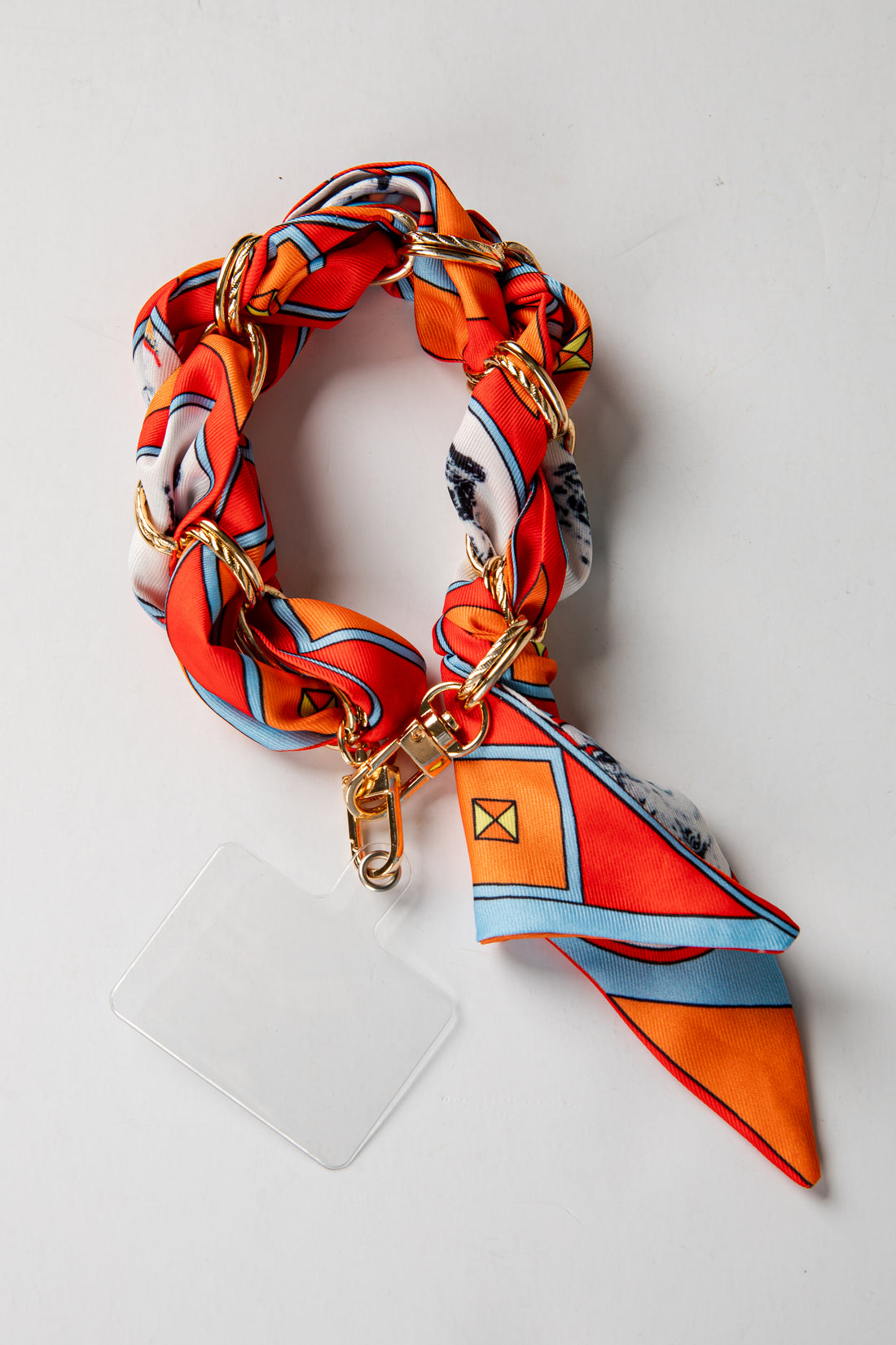 Colorful scarf with gold chain and phone case on a white background