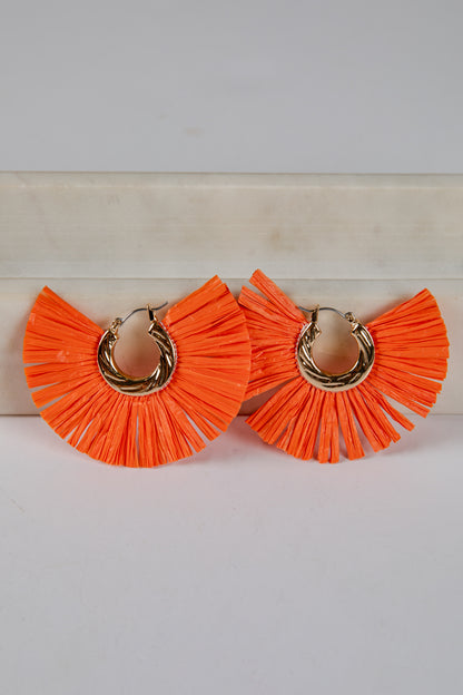 Orange ruffled earrings with gold hoops on a light background