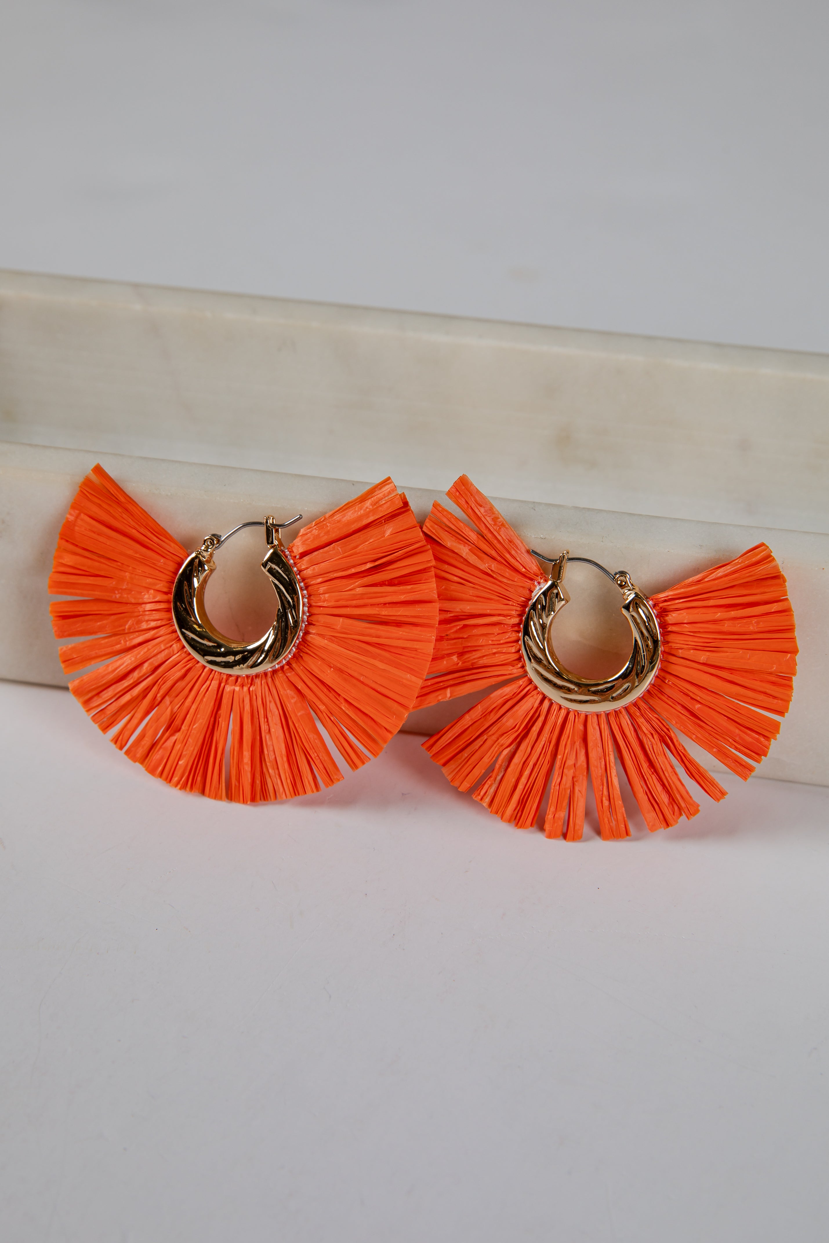Orange ruffled earrings on a white background
