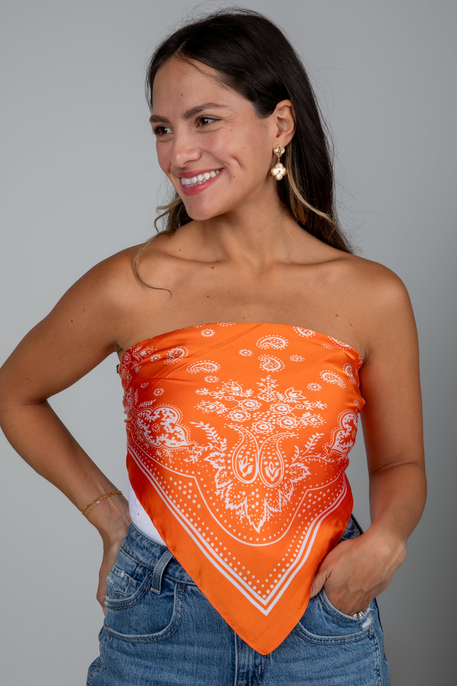 Woman wearing an orange bandana top with a gray background