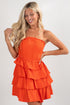 Woman wearing an orange tiered dress on a white background