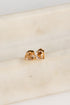 Gold earrings with orange gemstones on a light beige surface