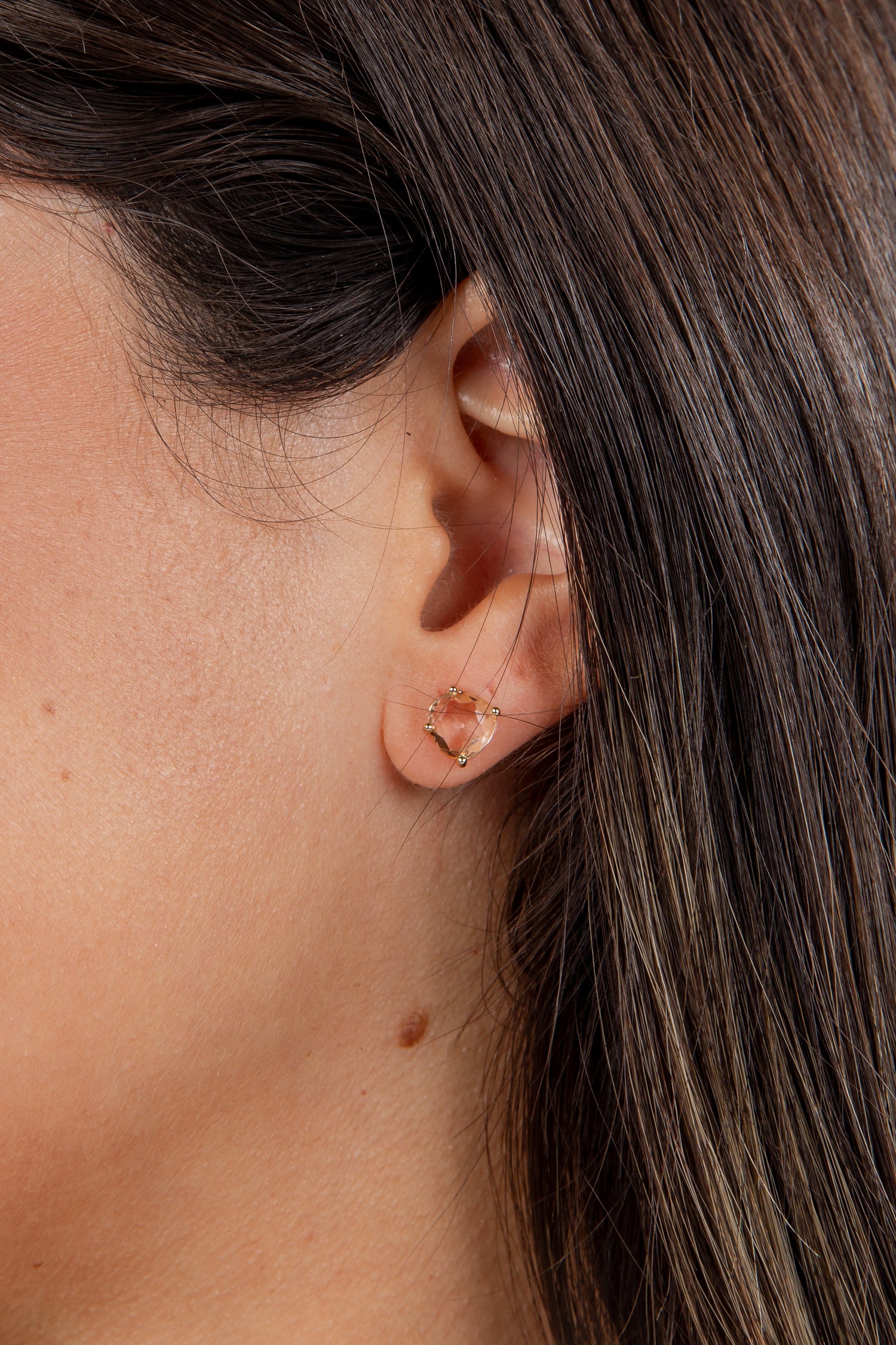 Close-up of an ear with a gold earring against a blurred background