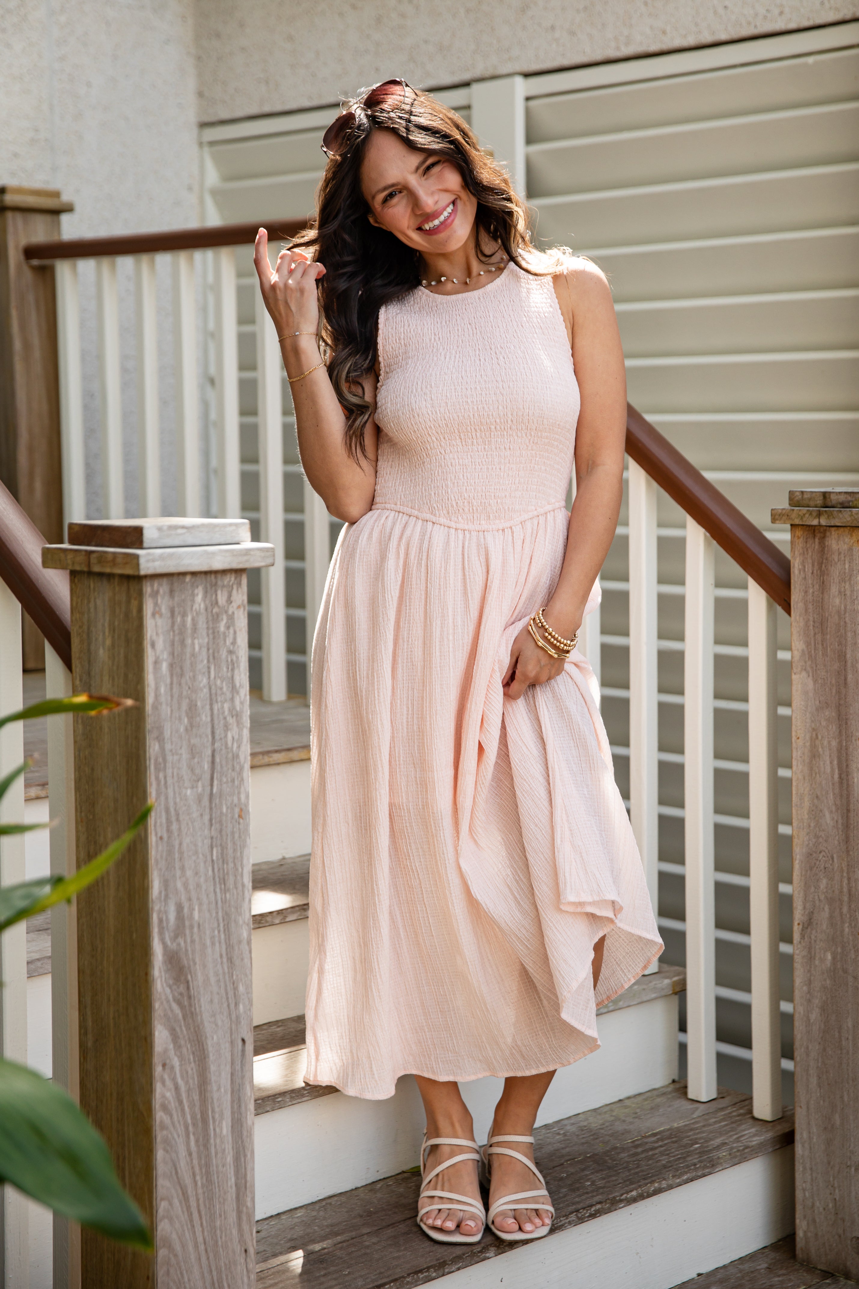 Woman in a light pink dress standing on a staircase