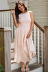 Woman in a light pink dress standing on a staircase