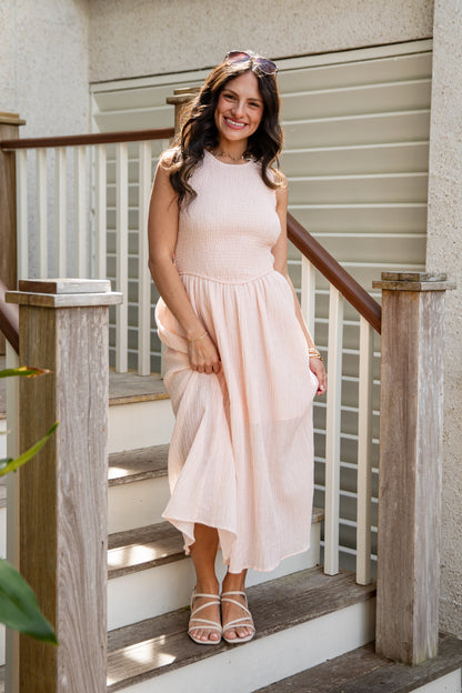 Woman in a light pink dress standing on a staircase