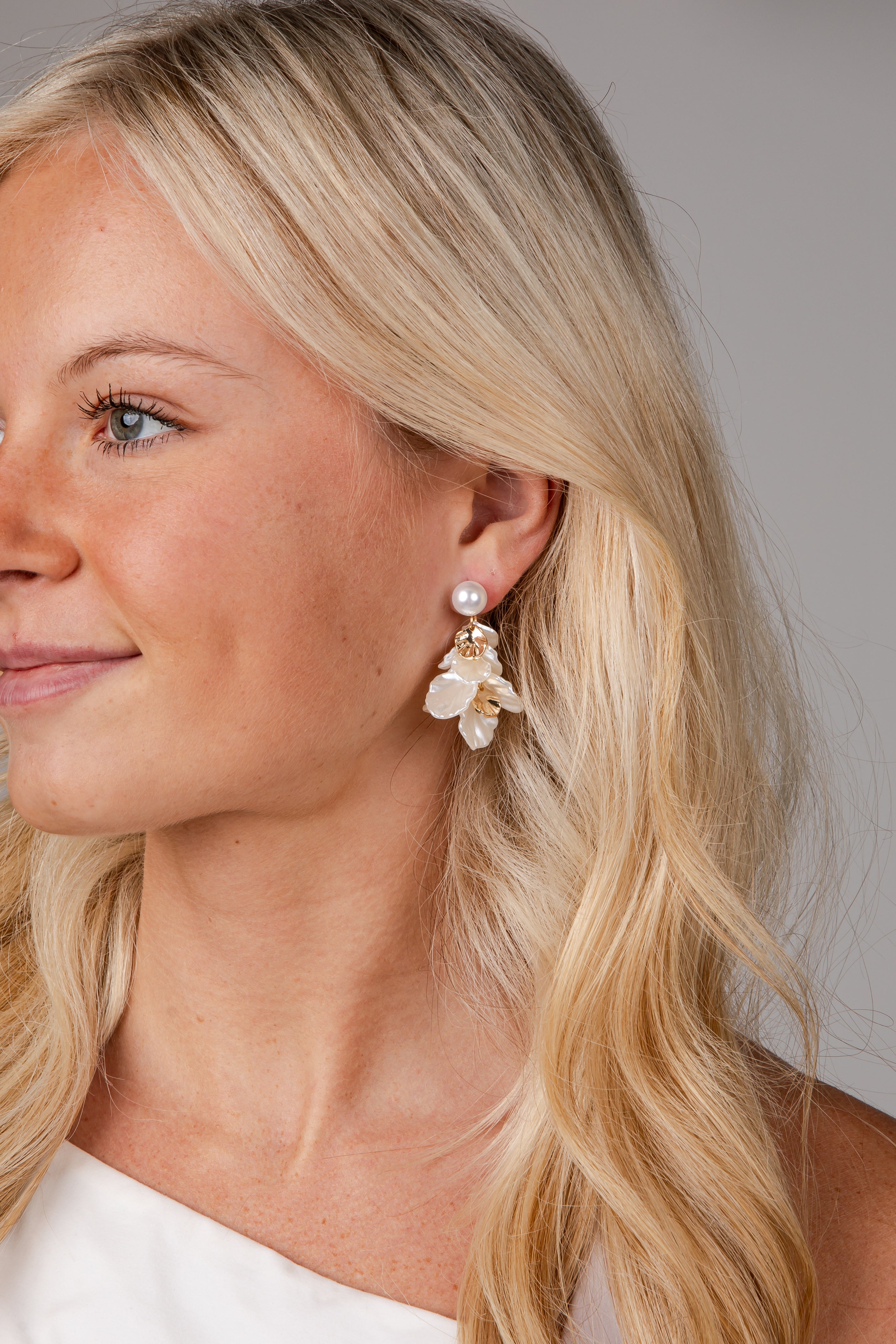 Close-up of a woman wearing pearl earrings with a neutral background