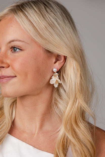 Close-up of a woman wearing pearl earrings with a neutral background