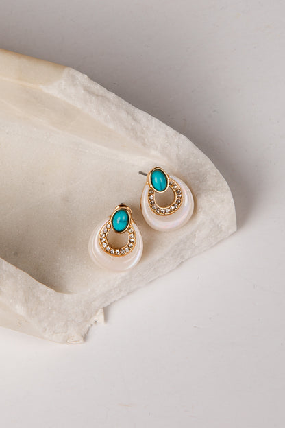 Pair of earrings with turquoise stones on a white stone surface