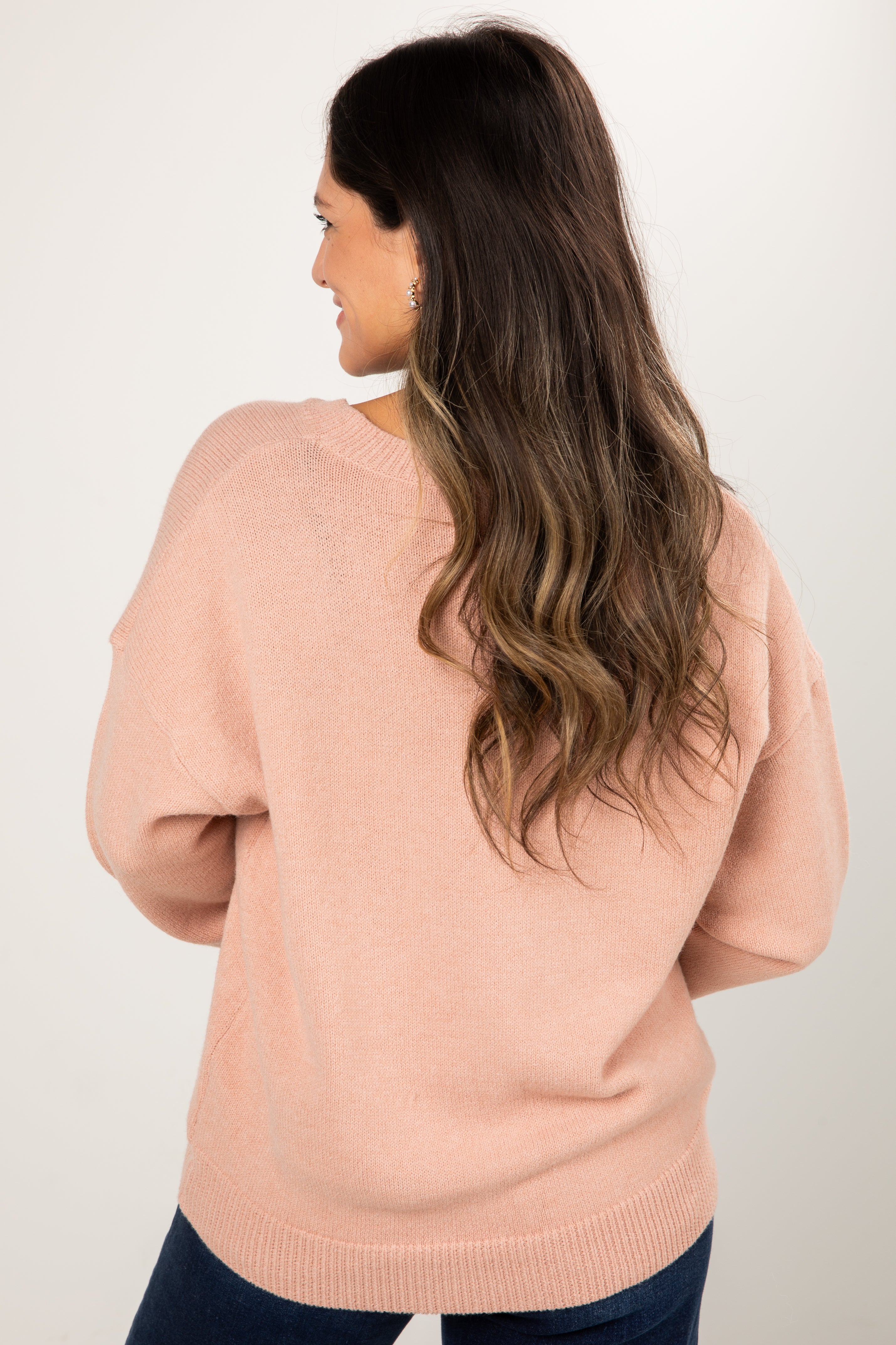 Woman wearing a pink sweater against a white background