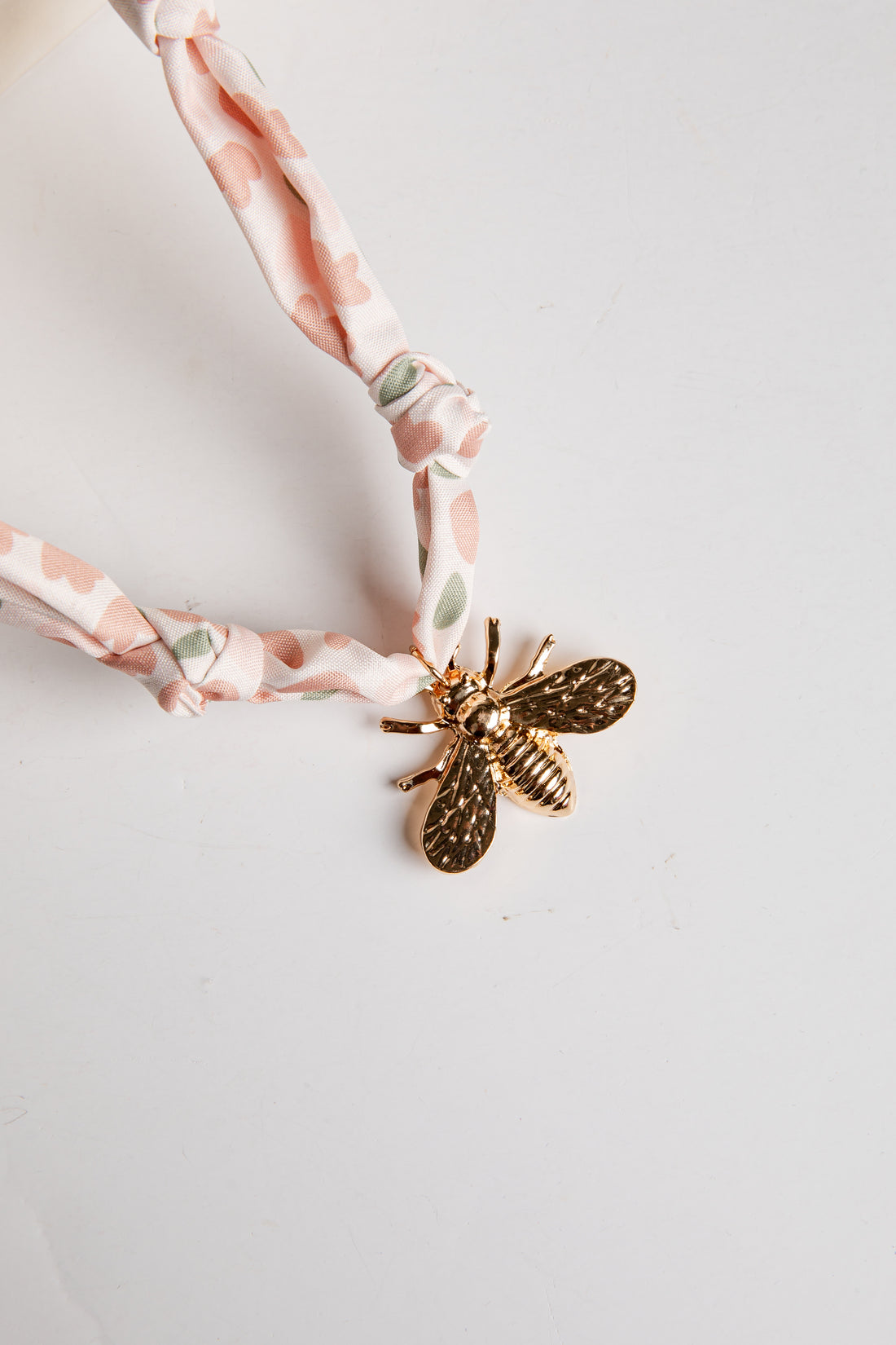 Necklace with a gold bee pendant on a white background