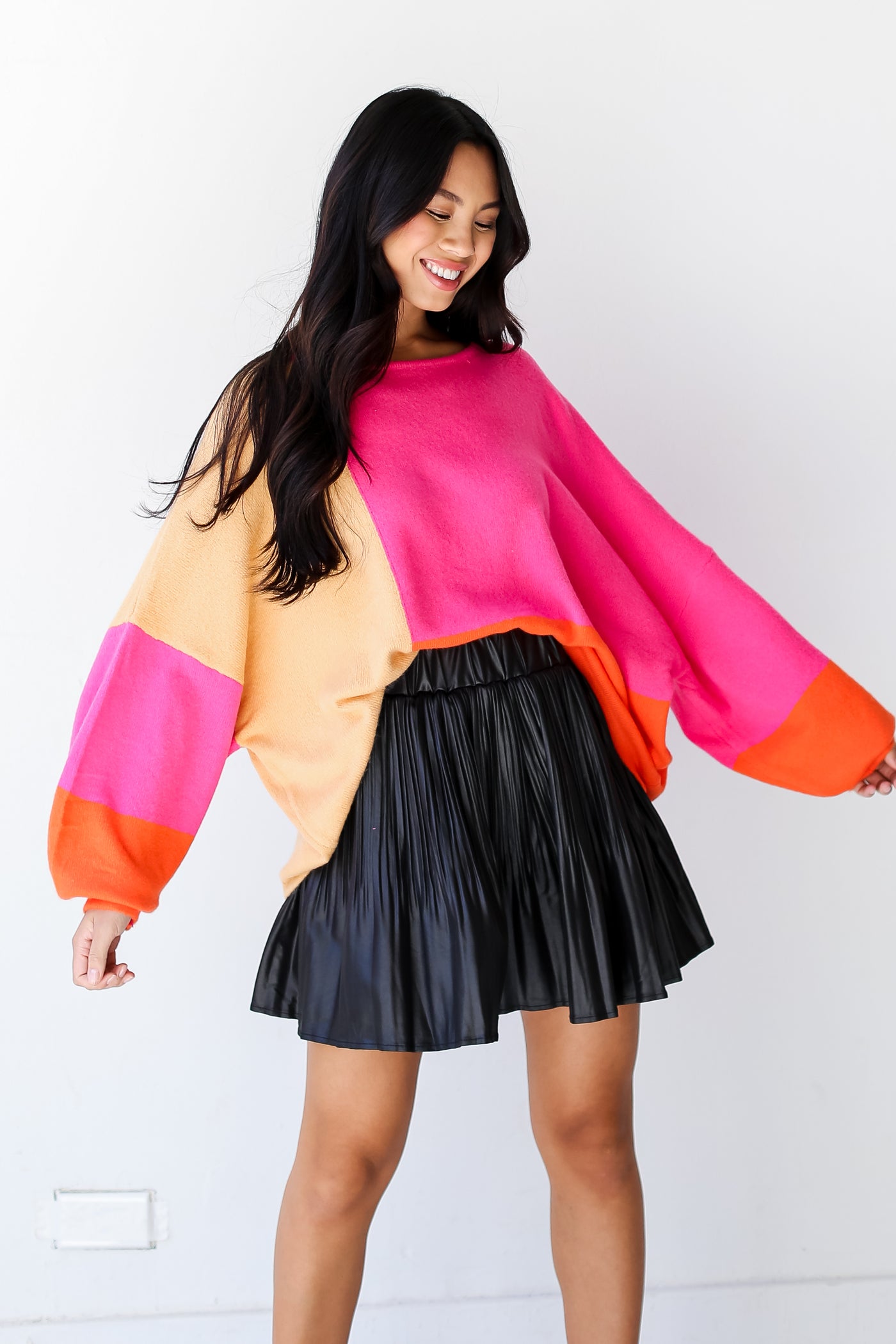 model wearing a Pink Color Block Sweater with a black leather mini skirt