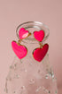 Pink heart-shaped earrings with gold accents on a pink background